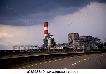Stock Image - Factory and an industrial chimney, by an asphalt road. Fotosearch