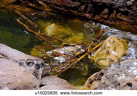 Stock Photography - Garbage and wooden poles floating on water. Fotosearch