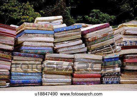 Stock Image - Old cushions and mattresses in stacks, in a junkyard. Fotosearch