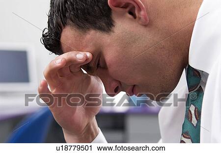 Stock Image - Businessman at desk with headache. Fotosearch