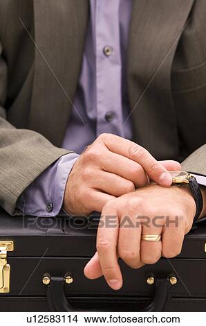 Picture - Businessman with briefcase checking his watch. Fotosearch