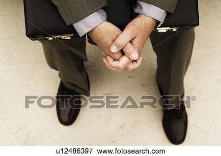 Stock Photo - Businessman with briefcase sitting on bench. Fotosearch