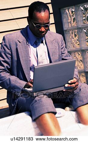 Stock Image - Businessman on laptop by hot tub. Fotosearch