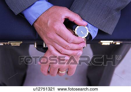 Stock Image - Businessman with briefcase checking his watch. Fotosearch