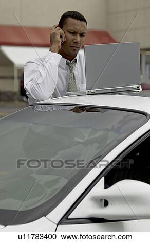 Businessman working on laptop on car View Large Photo Image Stock Image - Businessman working on laptop on car. Fotosearch