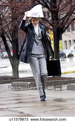 Stock Image - Businesswoman walking in the rain. Fotosearch