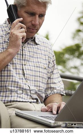 Man on phone with laptop View Large Photo Image Stock Image - Man on phone with laptop. Fotosearch