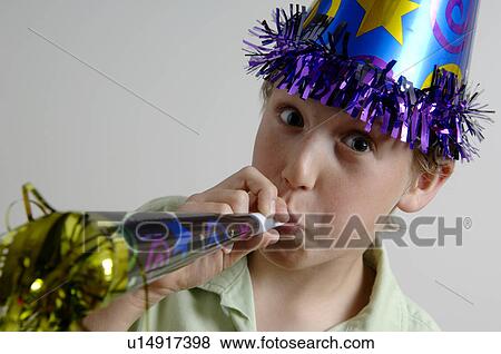 Stock Photo - Boy wearing party glasses and blowing noisemaker. Fotosearch