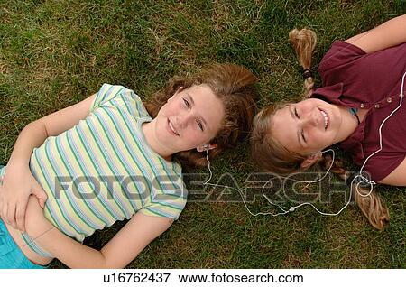 2 girls laying in grass head to head w/ipod Regina, Saskatchewan View Large Photo Image Stock Photo - 2 girls laying in grass head to head w/ipod Regina, Saskatchewan. Fotosearch