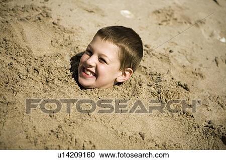 Stock Image - Boy, (7) buried up to his neck in the sand, Grand Beach Provincial Park, Manitoba, Canada. Fotosearch