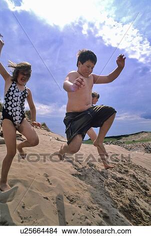 Kids jump from sand dune, summer day, Prince Edward Island, Canada View Large Photo Image Picture - Kids jump from sand dune, summer day, Prince Edward Island, Canada. Fotosearch