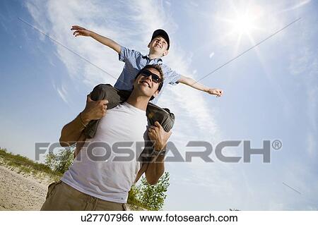 Low angle view with sun flare of man with boy (7) on his shoulders, Grand Beach Provincial Park, Manitoba, Canada View Large Photo Image Stock Photograph - Low angle view with sun flare of man with boy (7) on his shoulders, Grand Beach Provincial Park, Manitoba, Canada. Fotosearch