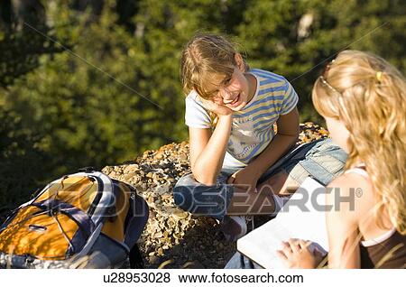 Two sisters seated outdoors, reading from a book, Saskatchewan View Large Photo Image Stock Photo - Two sisters seated outdoors, reading from a book, Saskatchewan. Fotosearch