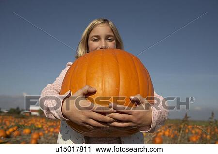 Young girl holding large organic pumpkin, Ladner, British Columbia, Canada View Large Photo Image Stock Image - Young girl holding large organic pumpkin, Ladner, British Columbia, Canada. Fotosearch