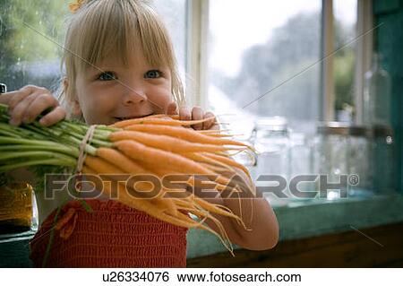 Stock Photograph - Young girl holds garden fresh carrots, Lumsden, Saskatchewan, Canada. Fotosearch