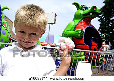 Stock Image - Boy standing in front of carnival ride. Fotosearch