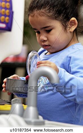 Picture - Girl playing with play kitchen. Fotosearch