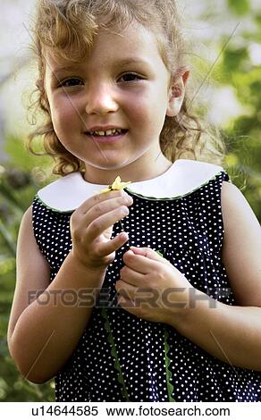 Stock Photography - Little girl holding a flower in her hands. Fotosearch