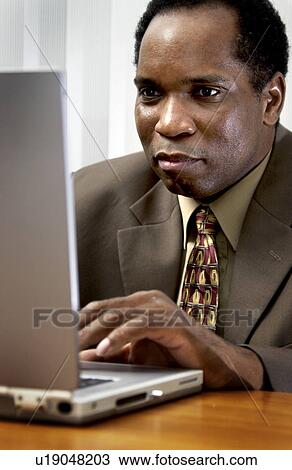 Stock Image - African American man working on laptop. Fotosearch