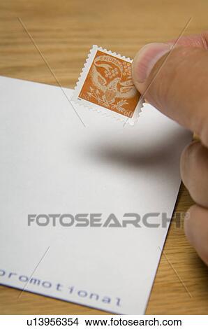 Picture - Man putting US stamp on envelope. Fotosearch