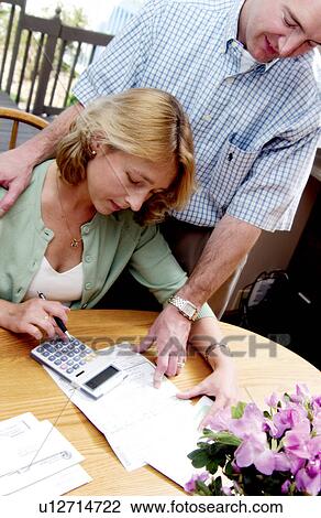 Stock Image - Couple looking over bills. Fotosearch