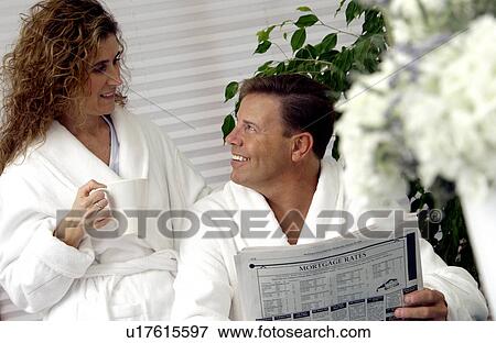 Couple sitting at table reading newspaper View Large Photo Image Stock Photo - Couple sitting at table reading newspaper. Fotosearch