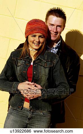 Stock Photograph - Teenagers leaning against a yellow wall. Fotosearch