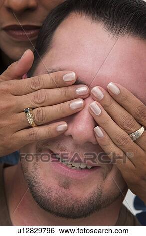 Woman putting her hands over Hispanic mans eyes View Large Photo Image Stock Photograph - Woman putting her hands over Hispanic mans eyes. Fotosearch