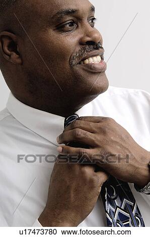 Stock Image - African American businessman adjusting his tie. Fotosearch
