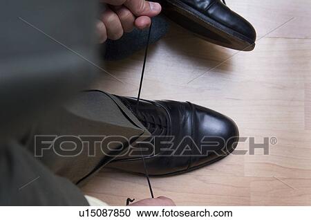 Stock Image - Businessman tying his shoes. Fotosearch