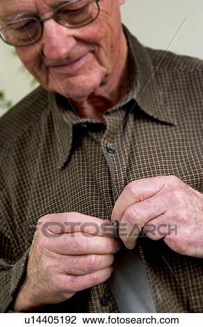 Stock Image - Senior man buttoning his shirt. Fotosearch