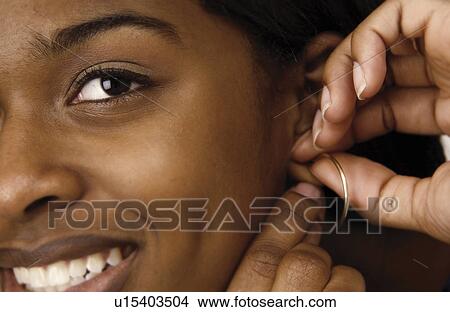 Woman putting on earring View Large Photo Image Picture - Woman putting on earring. Fotosearch