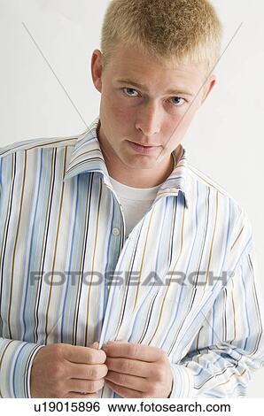 Young man buttoning his shirt View Large Photo Image Stock Photograph - Young man buttoning his shirt. Fotosearch