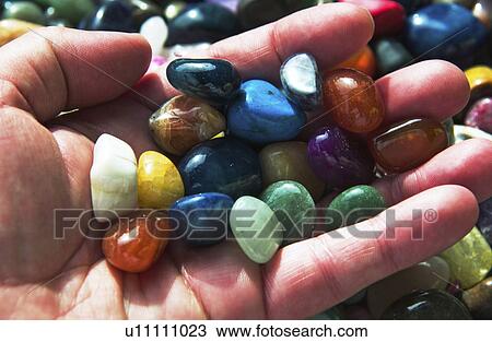 Stock Image - Hand holding colorful stones. Fotosearch