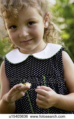 Stock Photograph - Little girl holding a flower in her hands. Fotosearch