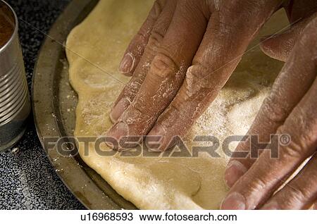 Stock Image - Man spreading pizza dough. Fotosearch