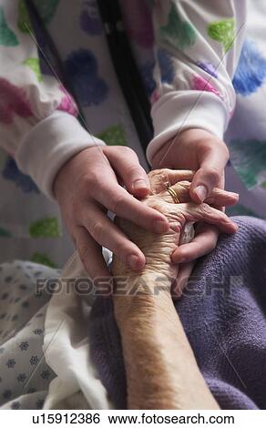 Senior woman holding hands with nurse View Large Photo Image Stock Photograph - Senior woman holding hands with nurse. Fotosearch