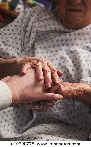 Senior woman in wheelchair holding hands with nurse View Large Photo Image Stock Photo - Senior woman in wheelchair holding hands with nurse. Fotosearch