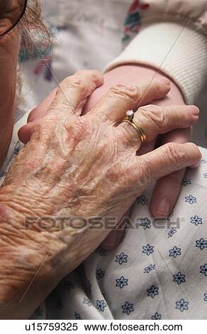 Stock Photography - Senior woman in wheelchair holding hands with nurse. Fotosearch