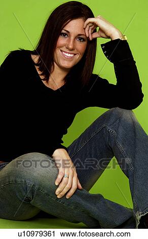 Stock Image - Young woman sitting against a stool. Fotosearch