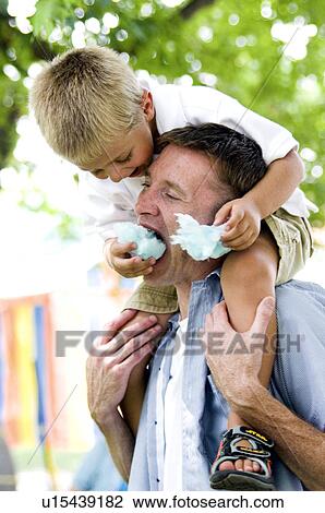 Stock Image - Boy feeding man cotton candy. Fotosearch