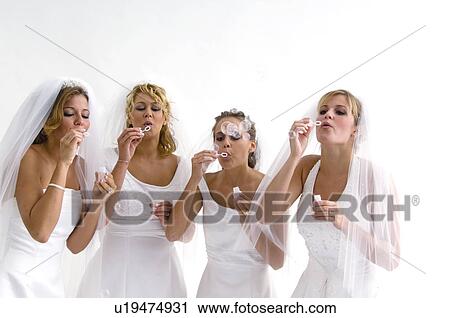 Stock Image - Group of brides blowing bubbles. Fotosearch