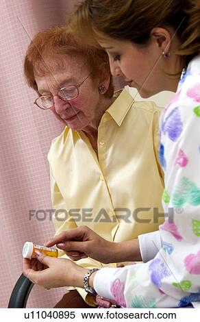 Stock Photography - Nurse giving senior woman a bottle of pills. Fotosearch