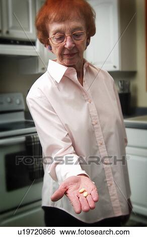 Stock Photograph - Senior woman holding pill. Fotosearch
