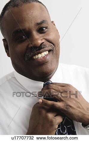 Stock Image - African American businessman adjusting his tie. Fotosearch