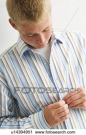 Young man buttoning his shirt View Large Photo Image Stock Image - Young man buttoning his shirt. Fotosearch