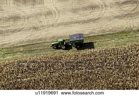 Stock Image - Aerial shot of farmer harvesting crops. Fotosearch