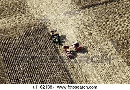 Stock Photo - Aerial shot of farmer harvesting crops. Fotosearch