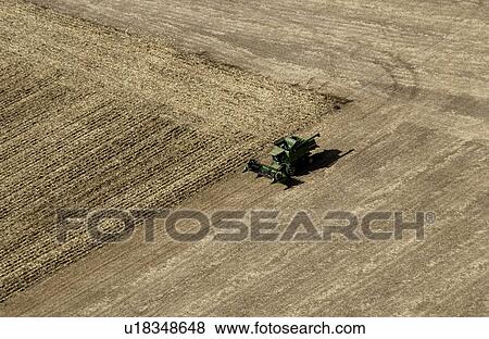 Stock Photo - Aerial shot of farmer harvesting crops. Fotosearch