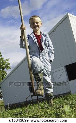 Stock Photo - Boy standing with pitchfork. Fotosearch